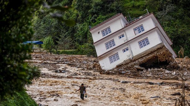 A three-story house tilted at an angle after its foundation was washed away by a landslide